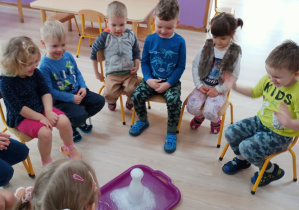 Dzieci oglądają eksperyment z wody, sody i octu